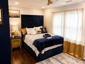 A bedroom with a bed, bedside table, lamp, and curtains.
