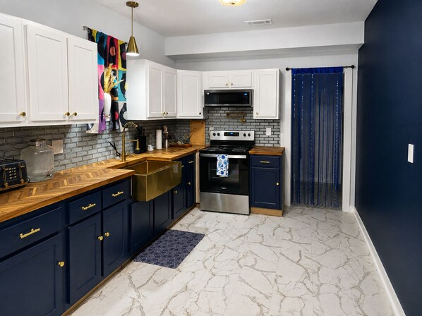 A modern kitchen with white cabinets, a stainless steel oven, and a black microwave.