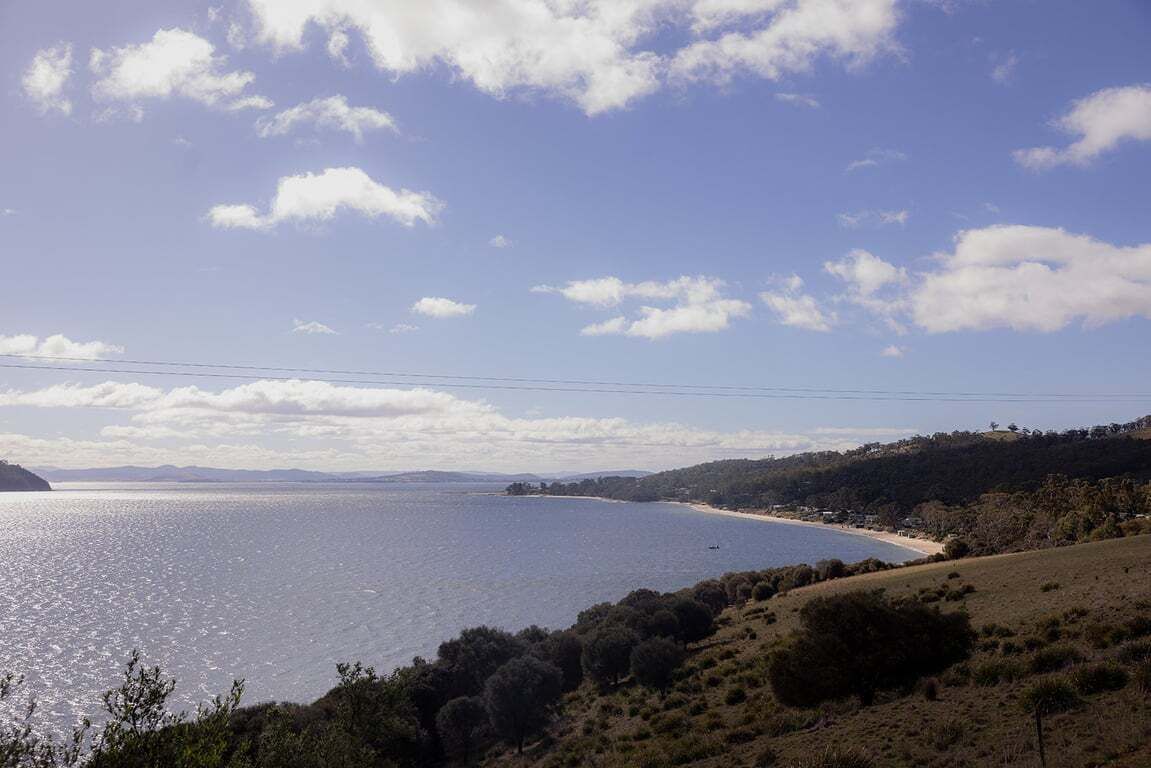 A coastal landscape with a clear sky, a body of water, and a hilly terrain.