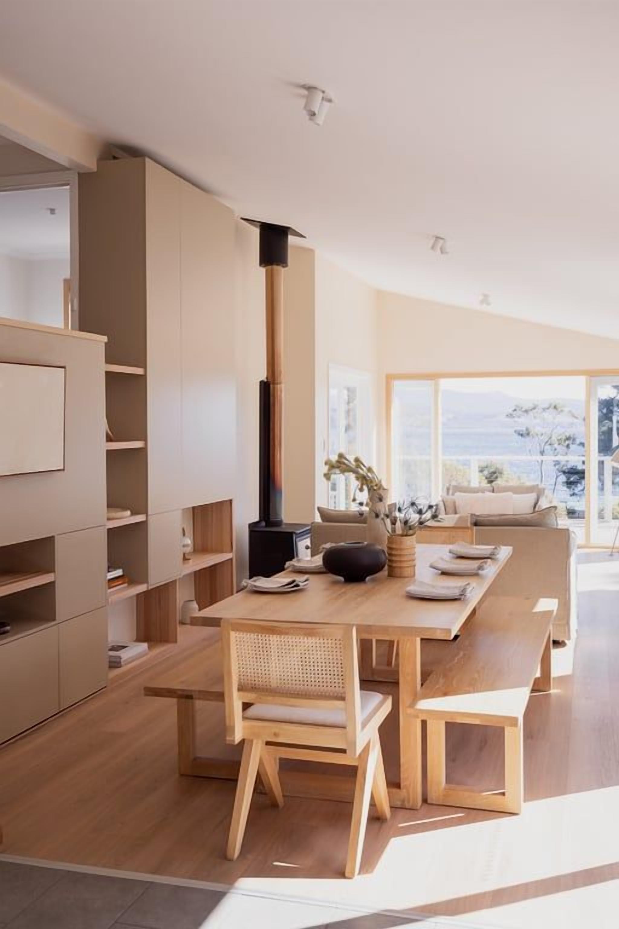 A modern kitchen with a central island, wooden chairs, and built-in shelving.