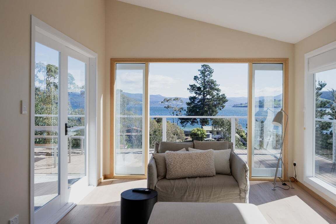 A modern living room with a large window, a sofa, and a lamp.