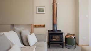A cozy living room with a sofa, a fireplace, and a framed picture on the wall. - Graceys Beach House Dennes Point (Kingborough)