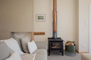 A cozy living room with a sofa, a fireplace, and a framed picture on the wall. - Graceys Beach House Dennes Point (Kingborough)