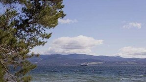 A beach with white tents and a clear view of the sea and distant mountains. - Graceys Beach House Dennes Point (Kingborough)