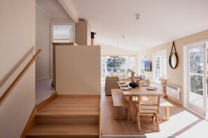 Un interior modern amb una escala que condueix a una zona de menjador, grans finestres i vista a l'exterior.