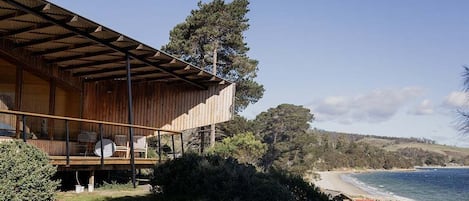 A wooden building with a balcony overlooking a beach.