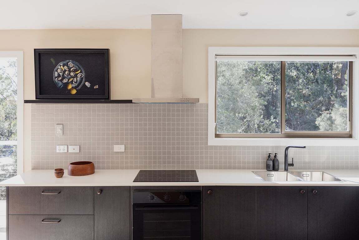 Eine moderne Küche mit großem Fenster, einem Einbauofen und einer Spritzschutzwand.
