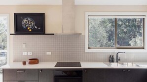 A modern kitchen with a large window, a built-in oven, and a backsplash. - Graceys Beach House Dennes Point (Kingborough)