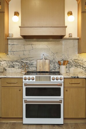 A kitchen with wooden cabinets, a marble backsplash, and a white stove with four burners.