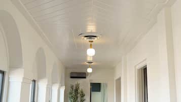 A hallway with white walls, a wooden floor, and a ceiling with a central light fixture.
