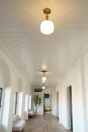 A hallway with white walls, a wooden floor, and a ceiling with a central light fixture.