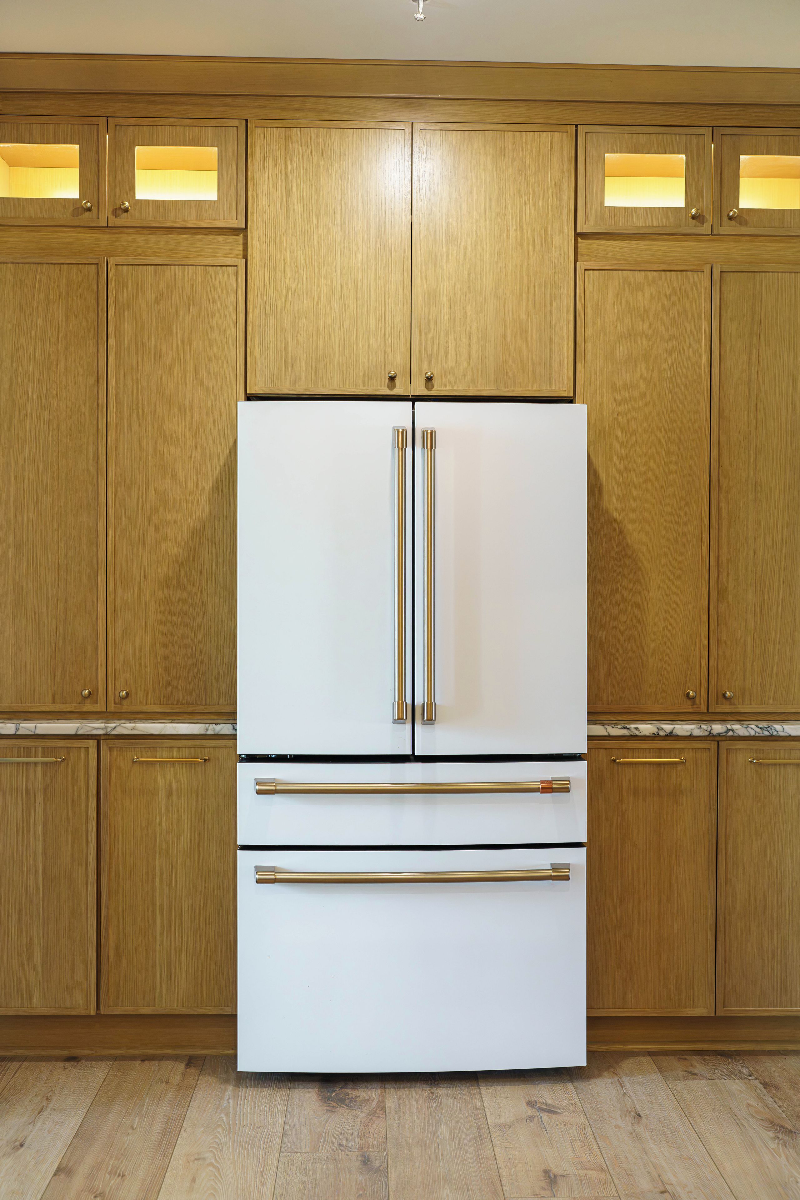 A kitchen with wooden cabinets, a white refrigerator, and a marble countertop.