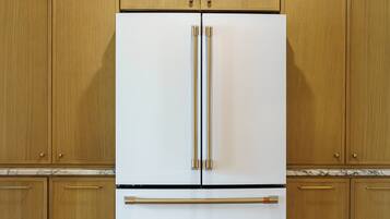 A kitchen with wooden cabinets, a white refrigerator, and a marble countertop.