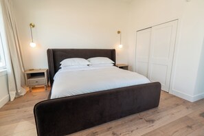 A bedroom with a large bed, bedside tables, a wardrobe, and a window with curtains.
