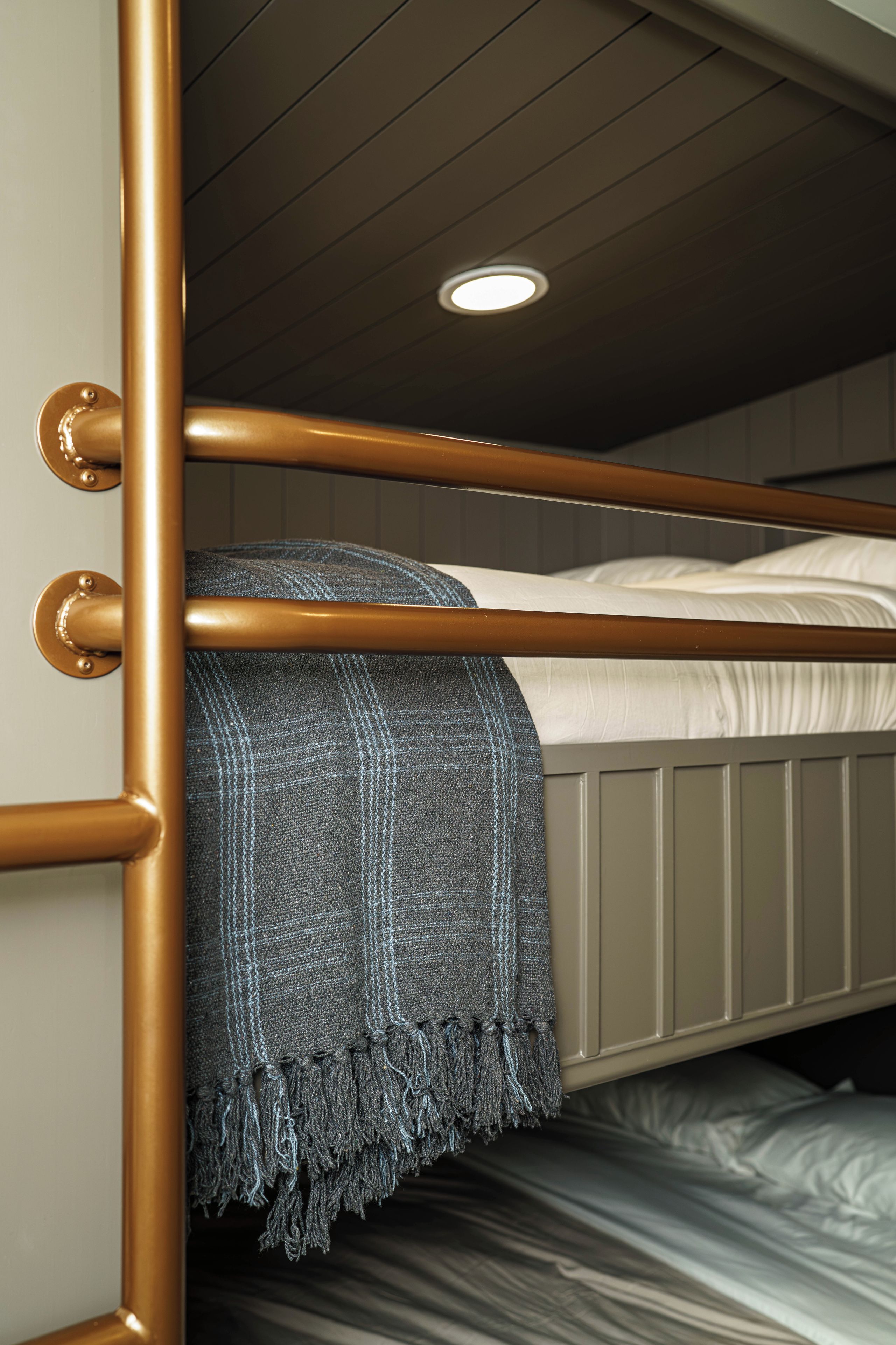 Uma cama box com estrutura de metal, cobertor cinza e colchão branco.