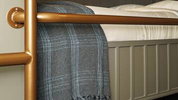 Uma cama box com estrutura de metal, cobertor cinza e colchão branco.