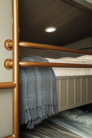 A bunk bed with a metal frame, a grey blanket, and a white mattress.
