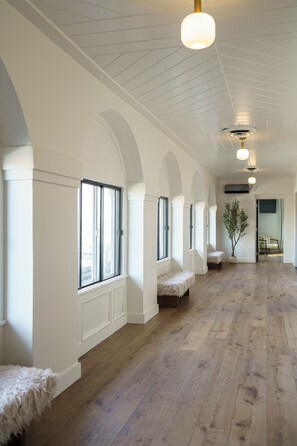 Un hall d’entrée spacieux avec des murs blancs, un plancher en bois et de nombreuses fenêtres.