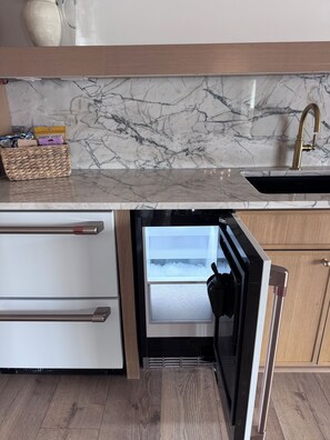 A kitchen with a built-in refrigerator, a marble backsplash, and a wooden countertop.