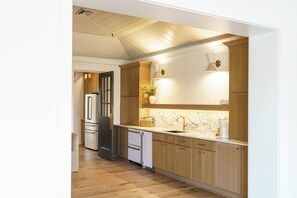 A modern kitchen with wooden cabinets, a marble countertop, and a built-in oven.