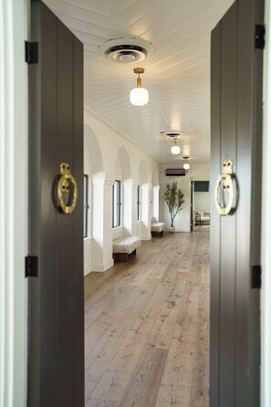 A hallway with wooden flooring, white walls, and a ceiling with recessed lighting.
