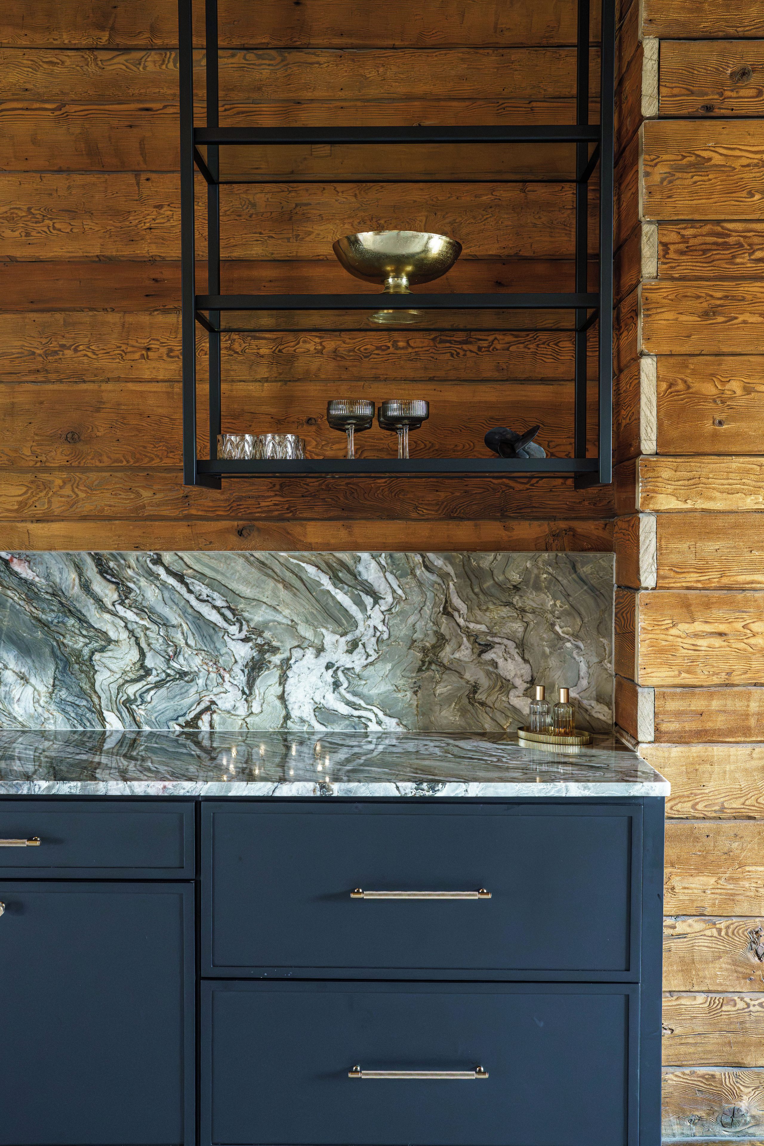 A kitchen with a wooden wall, a marble backsplash, and a black cabinet with drawers.