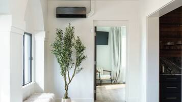 A spacious hallway with a wooden floor, a white bench, a potted plant, and a ceiling fan.