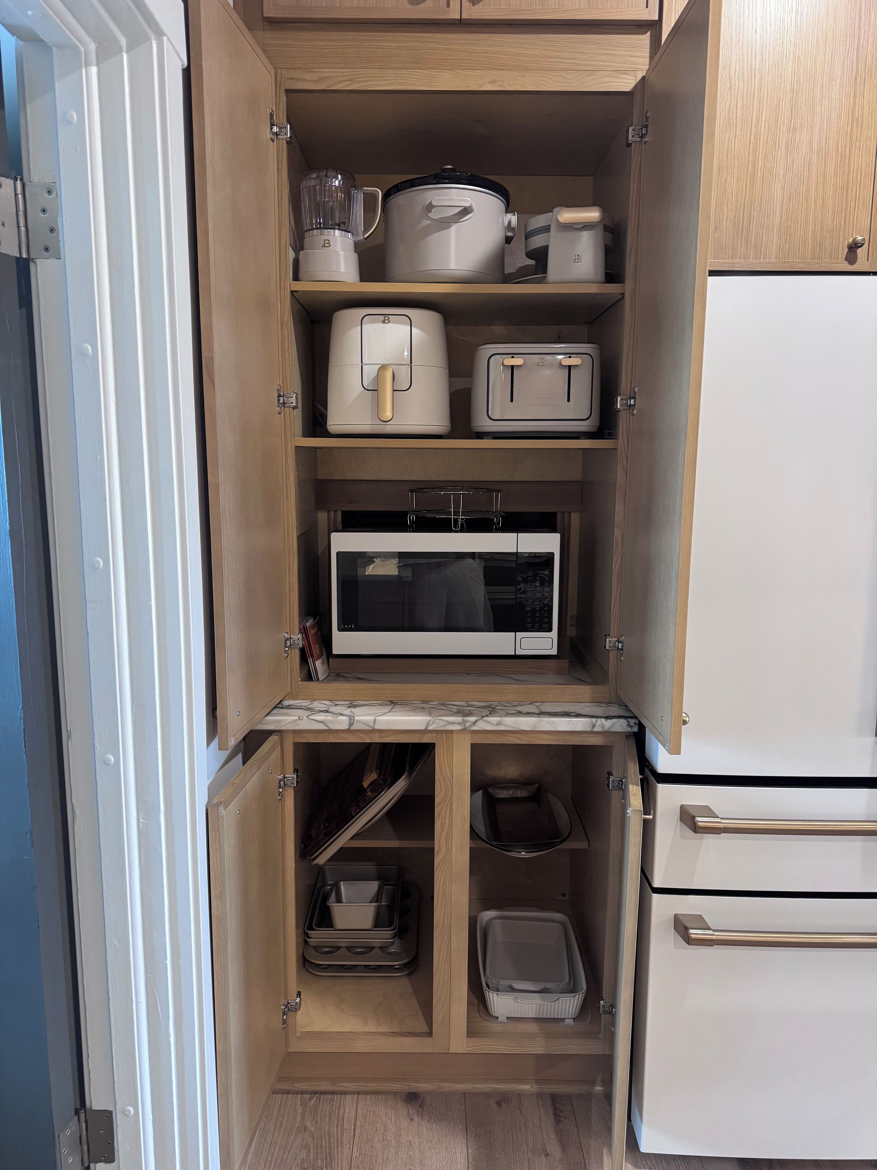 A compact kitchen with a microwave, toaster, blender, and storage cabinets.