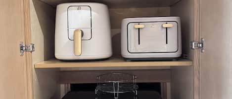Ein Küchenschrank mit Mikrowelle, Toaster, Mixer und Slow Cooker.