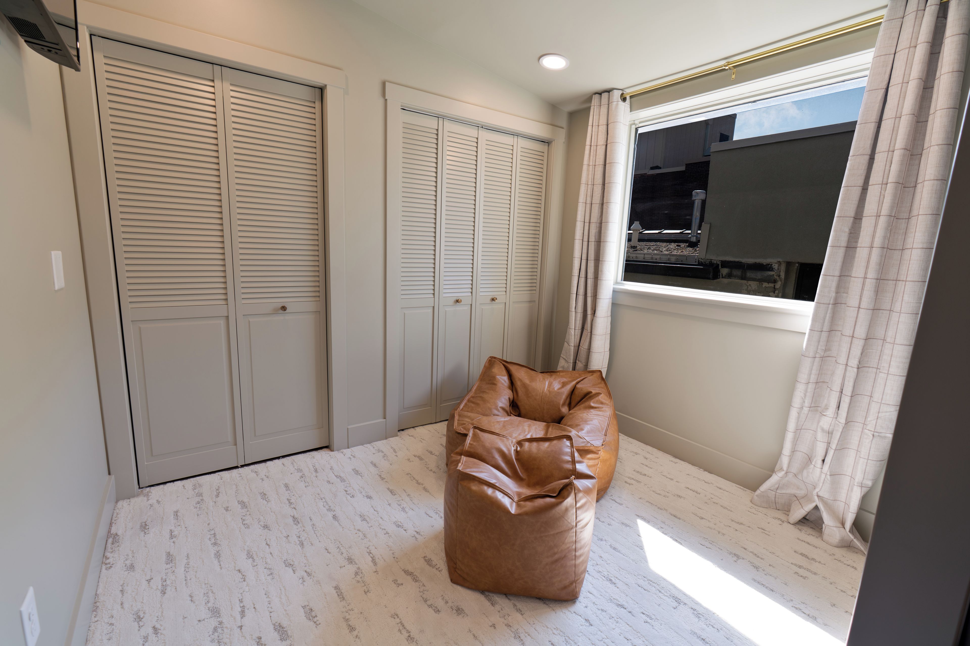 A room with a large closet, a window with curtains, and a bean bag chair.