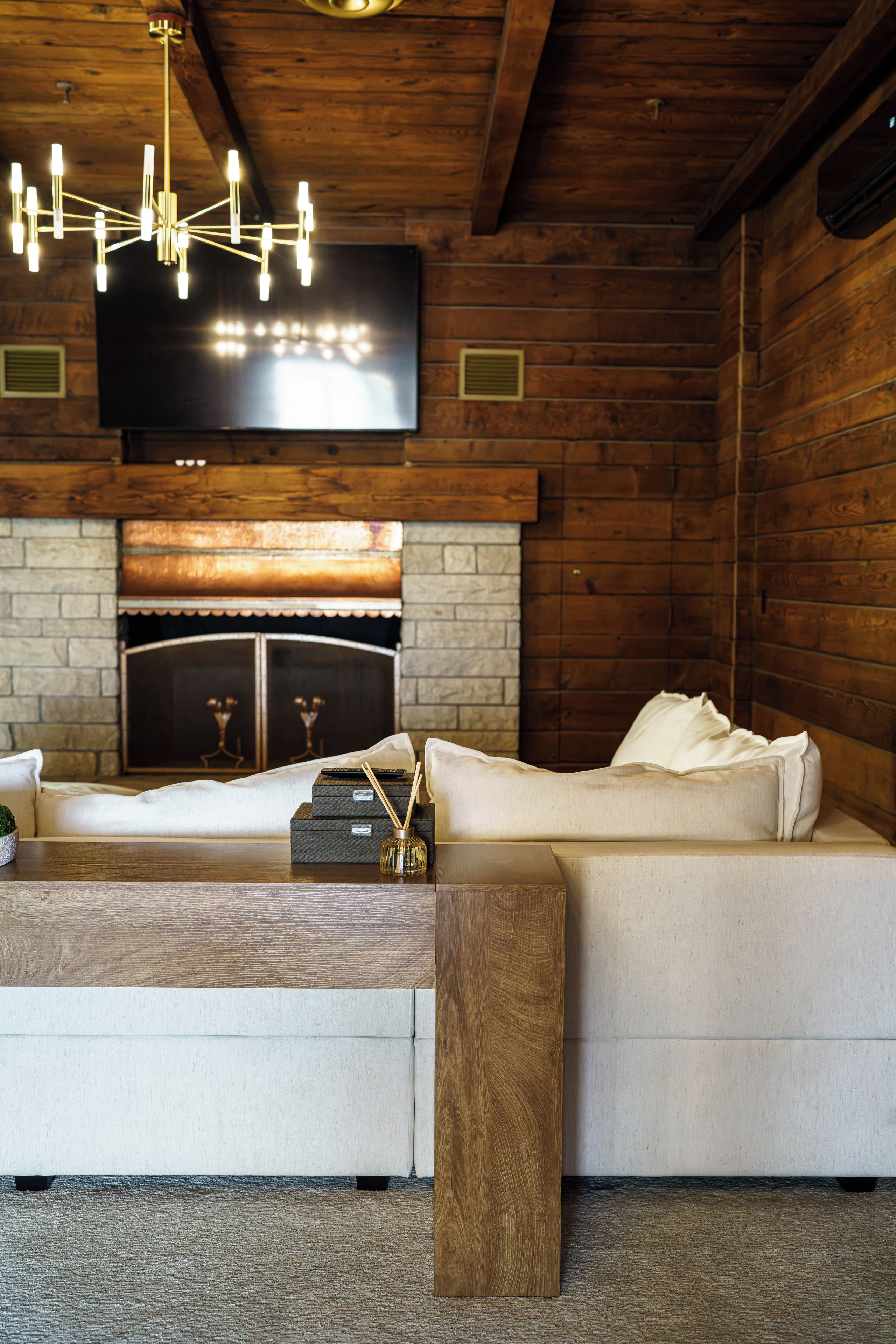 A modern living room with a fireplace, a sofa, a coffee table, and a TV mounted on the wall.