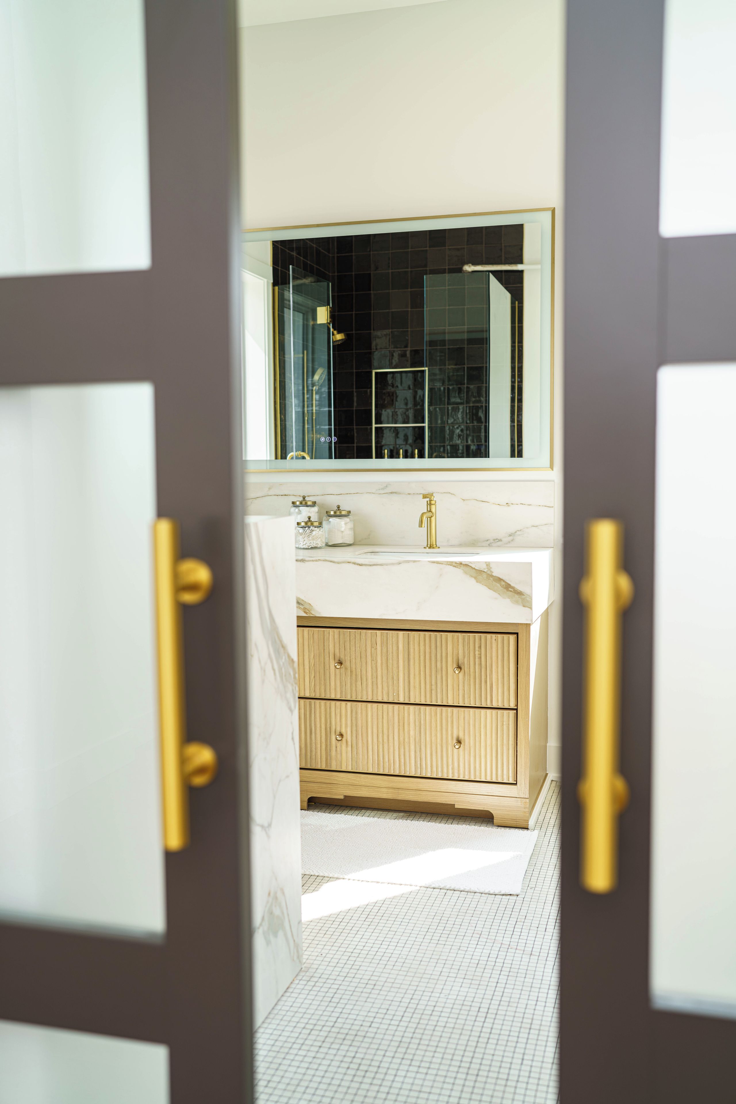 A bathroom with a marble countertop, a wooden vanity, and a large mirror.
