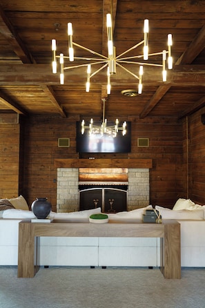 Un interior acogedor con techo de madera, chimenea, sofá y una lámpara moderna.
