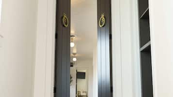 A staircase leading to a dark wooden door with a brass handle, white walls, and a light fixture on the ceiling.