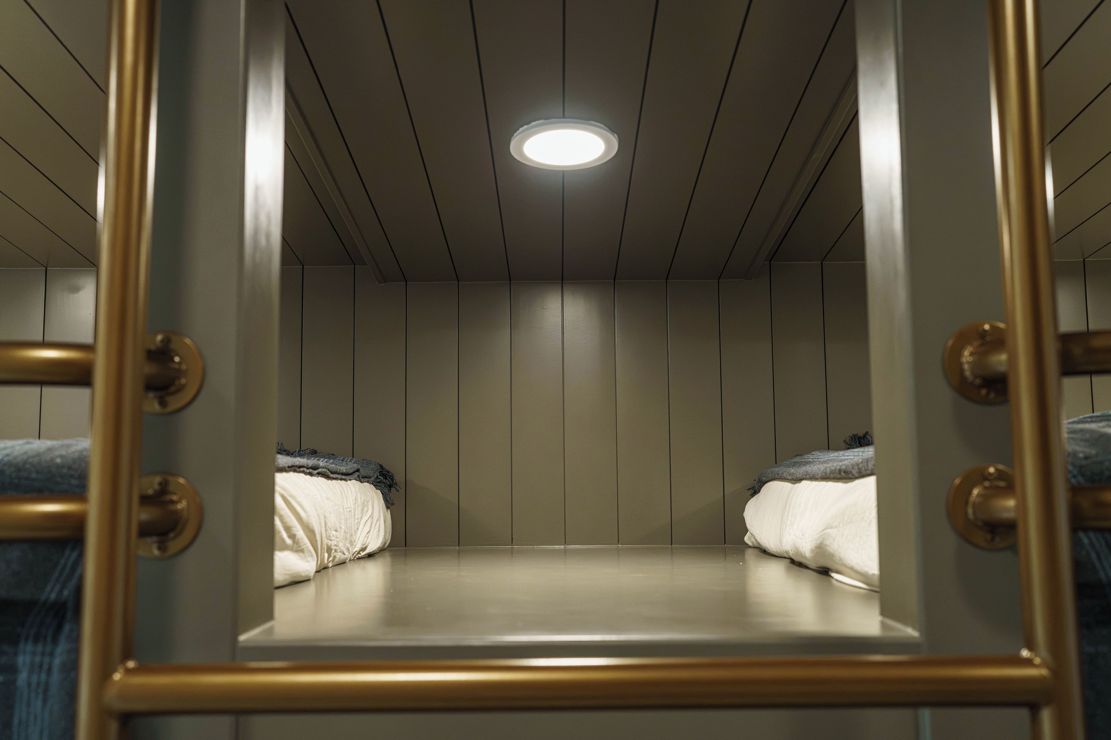 A room with bunk beds, a ceiling light, and a wooden wall.