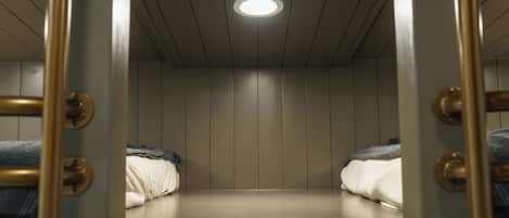 A room with bunk beds, a ceiling light, and a wooden wall.