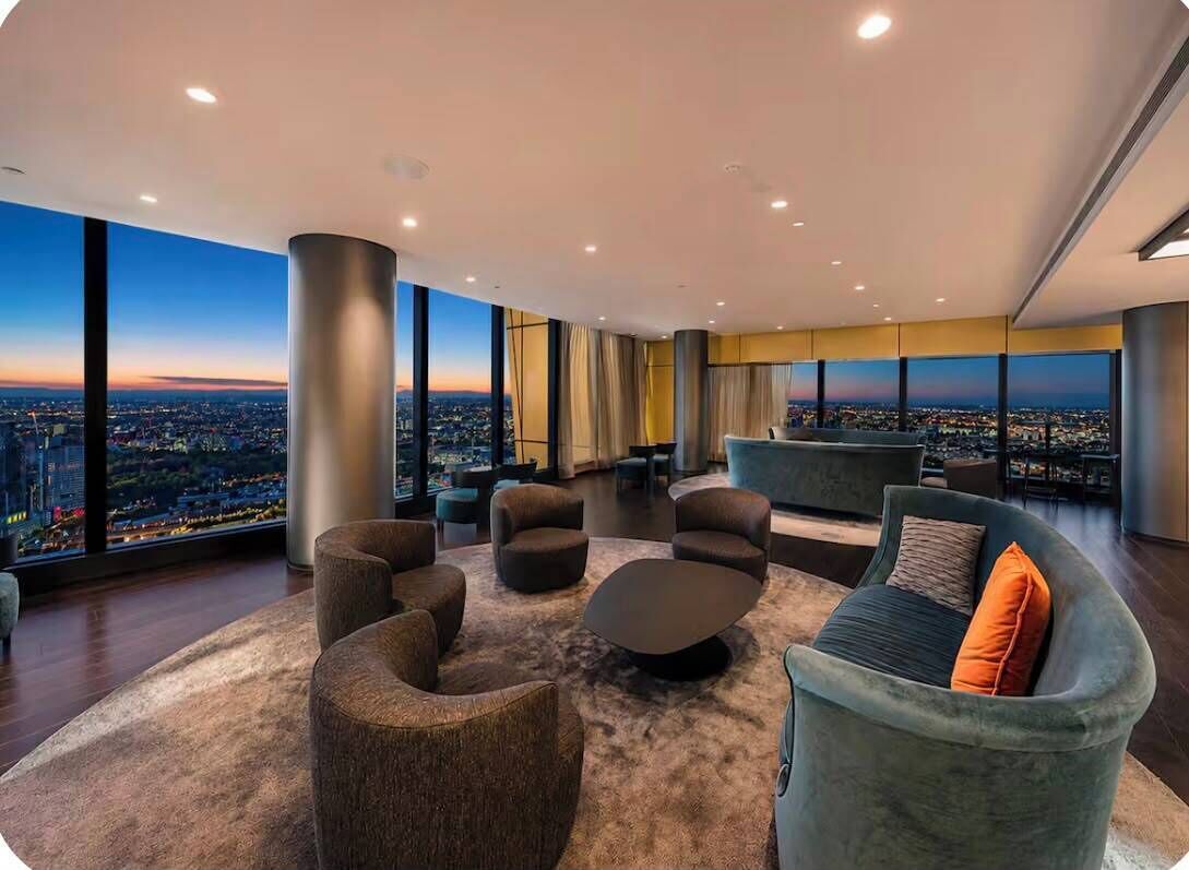 A modern lounge area with a panoramic city view, comfortable seating, and a large window.