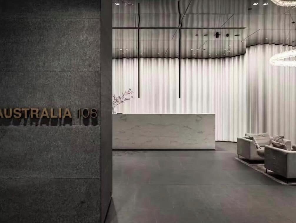 A reception area with a marble counter, modern lighting fixtures, and a large window with curtains.