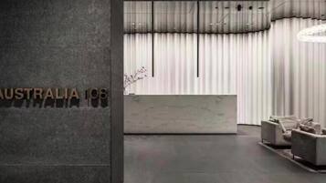 A reception area with a marble counter, modern lighting fixtures, and a large window with curtains.