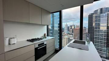 A modern kitchen with a city view, featuring a stove, oven, and a large window.