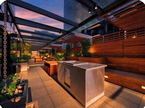Un espace extérieur aménagé en terrasse, avec un banc en bois, une table en acier inoxydable et une structure en forme de pergola.