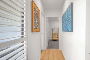 A hallway with a wooden floor, white walls, and a chair in the background. - Luxury by the lighthouse (Surf Coast)