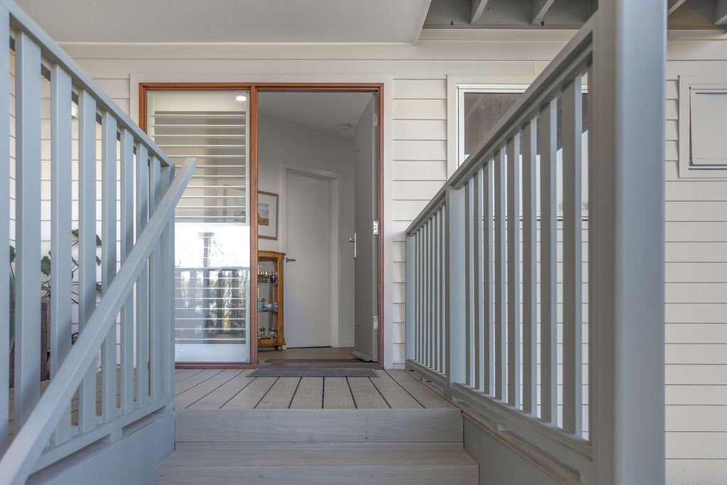A staircase with a wooden handrail and a glass door leading to another room.