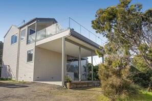 A two-story house with a balcony, a covered porch, and a gravel driveway. - Luxury by the lighthouse (Surf Coast)