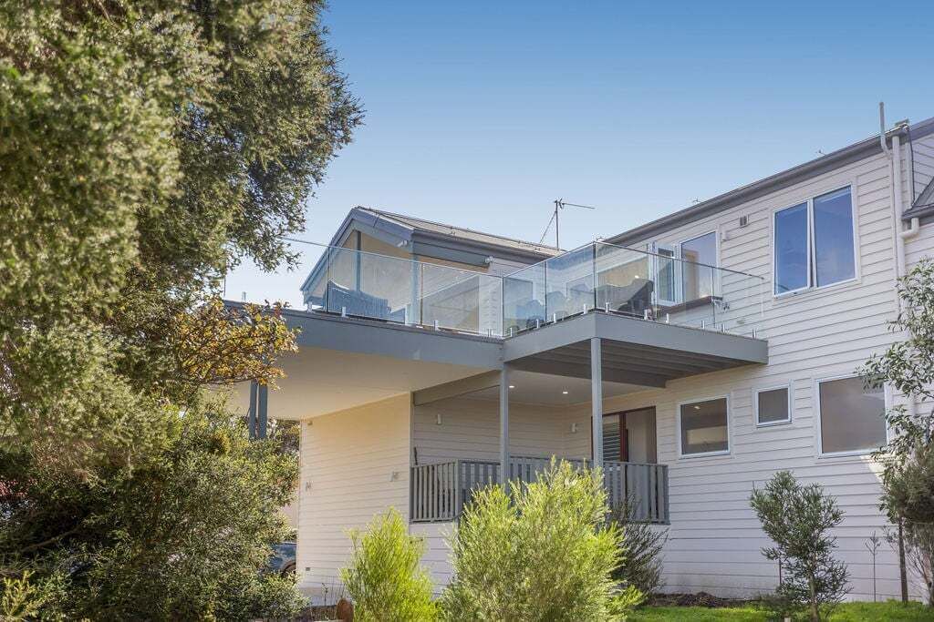 A modern two-story house with a balcony and a covered outdoor area.