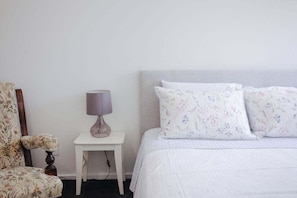 A bedroom with a bed, a nightstand, a lamp, and a chair. - Luxury by the lighthouse (Surf Coast)