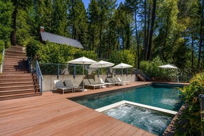 Piscina com deck de madeira, espreguiçadeiras e guarda-sóis.