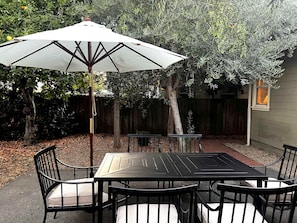 Eine Terrasse mit Tisch und Stühlen, einem Sonnenschirm und einem Holzzaun im Hintergrund.