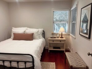 A bedroom with a bed, bedside table with a lamp, a clock, and a framed picture on the wall. - Plaza St Bungalow -Walk to Plaza, Tasting Included (Healdsburg)