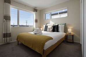 Une chambre d’hôtel avec un lit, deux tables de chevet, une fenêtre avec des rideaux et une vue sur l’extérieur.